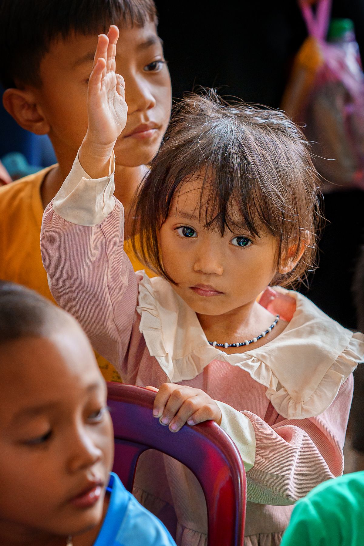 A young student raising her hand to answer in class